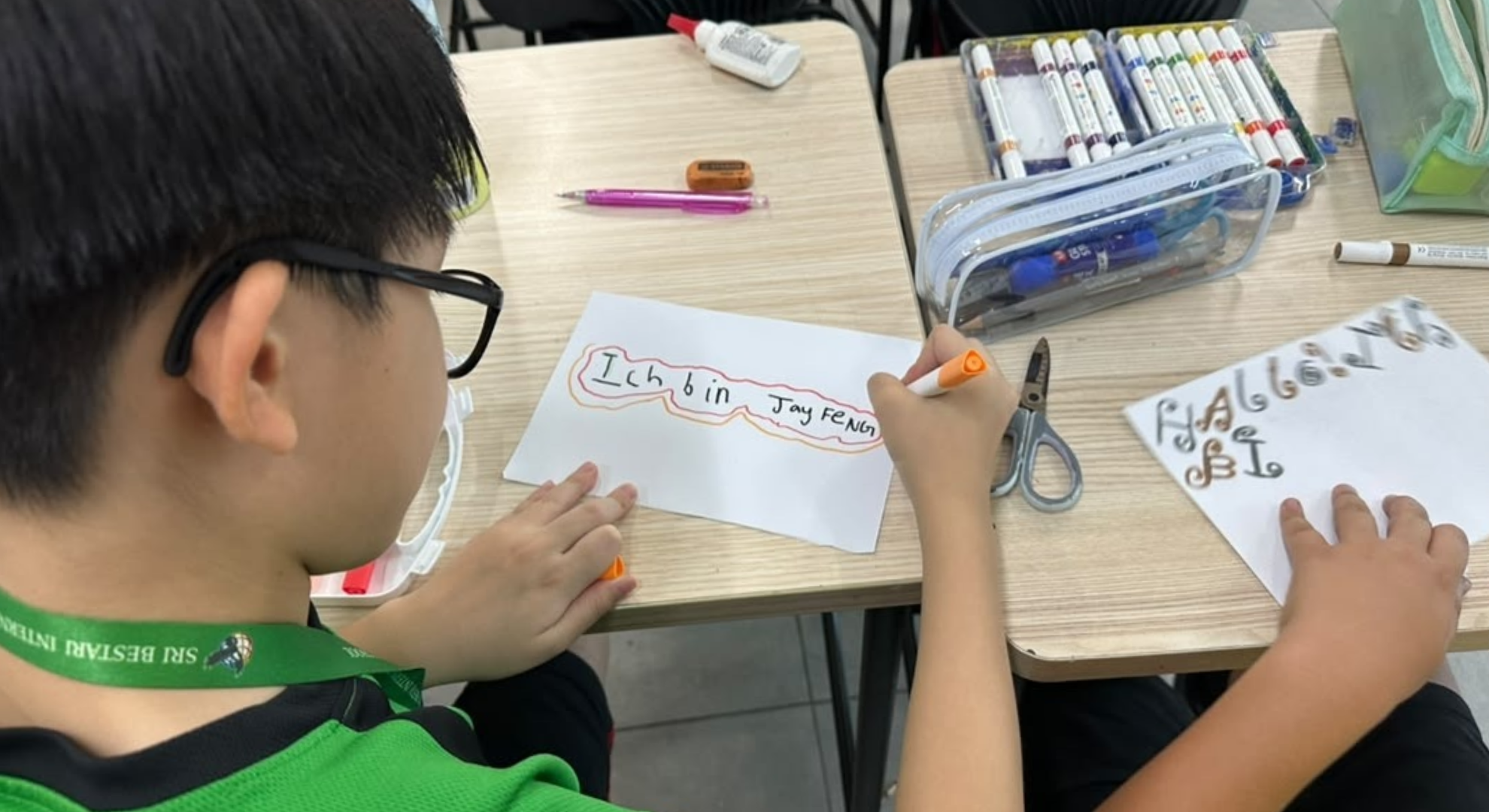 SBIS student writing German vocabulary on a worksheet during a German lesson