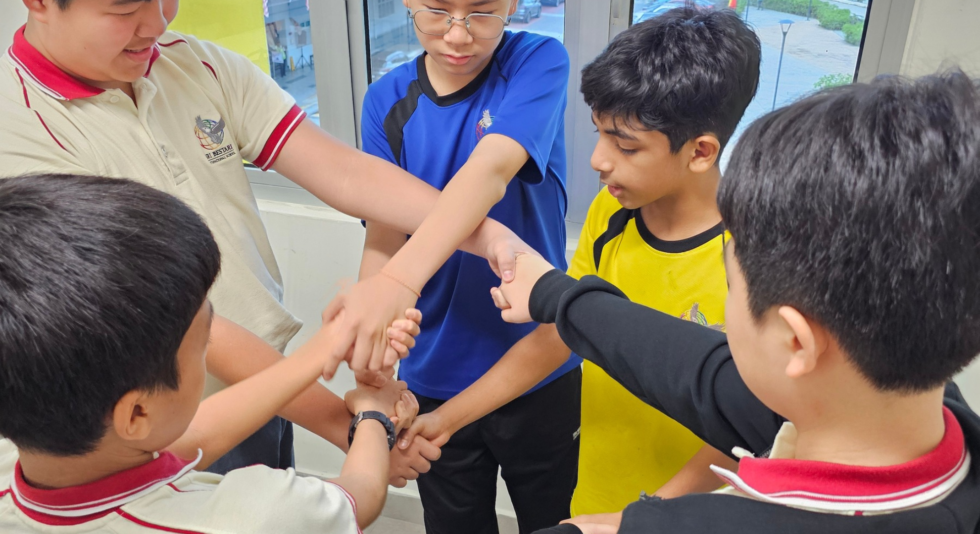 Students putting their hands together as a team at Sri Bestari International School